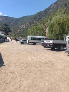 a group of cars and a bus parked in a dirt field at مخيم اقشور in Chefchaouen