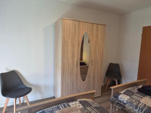 a bedroom with a wooden cabinet and two chairs at FeWo Marjenza in Wermelskirchen