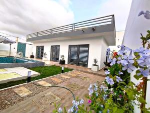 a white house with a swimming pool and flowers at Luxe villa 3 chambres Somone in Somone