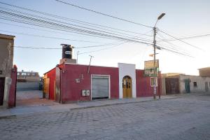 a red building on the side of a street at Hostal Terra Sal - Bed, Breakfast, Garage & Salar de Uyuni Tours in Uyuni