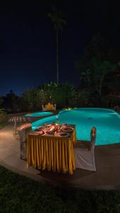 a table in front of a swimming pool at night at Indo Asia Heritage, Madikeri, formerly Hotel Coorg International in Madikeri