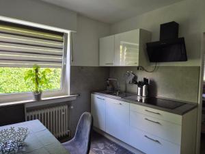 a kitchen with white cabinets and a sink and a window at FeWo Marjenza in Wermelskirchen +16 photos