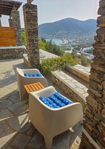 two chairs and a bench on a patio with a view at Panostria Apartments Sifnos in Sifnos