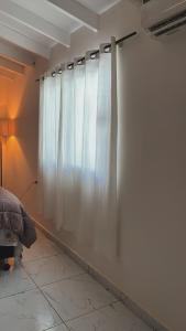 a bedroom with a curtain on a wall at Áurea hospedagem in Ciudad del Este