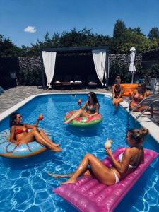 a group of women sitting on inflatables in a swimming pool at 4 TREES Airport Resort Apartments and Rooms in Velika Gorica