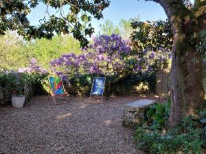 two chairs sitting under a tree with purple flowers at Le sabot de Madame in Lussac-les-Châteaux