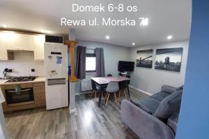 a kitchen and a living room with a couch and a table at Domki Morska in Rewa