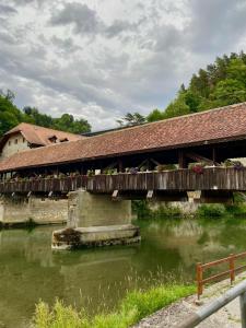 a wooden bridge over a river with a building at Cosy studio dans un quartier animé et pittoresque in Fribourg