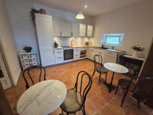 a kitchen with two tables and chairs and white cabinets at Boutiquezimmer Duchesse in Mirepoix