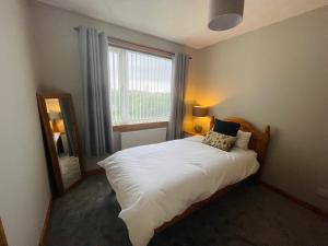 a bedroom with a bed and a mirror and a window at Tigh-na-lios, Inver in Inver