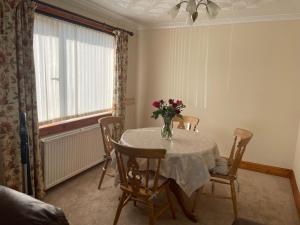 a dining room table with a vase of flowers on it at Tigh-na-lios, Inver in Inver