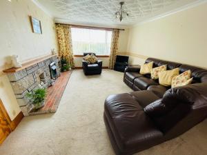a living room with a leather couch and a fireplace at Tigh-na-lios, Inver in Inver +1 photo