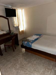 a bedroom with a bed and a desk and a mirror at Cid Hotel Mérida in Mérida