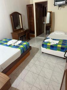 a bedroom with two beds and a desk and a mirror at Cid Hotel Mérida in Mérida