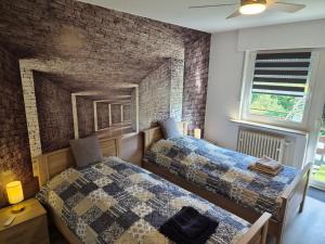 a bedroom with two beds and a brick wall at FeWo Marjenza in Wermelskirchen