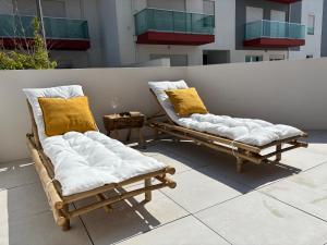 two chaise lounges with pillows on a patio at Alto Mar Apartment 2 in Atouguia da Baleia
