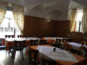 ein Esszimmer mit Tischen, Stühlen und Fenstern in der Unterkunft Pensione Città Vecchia in Locarno