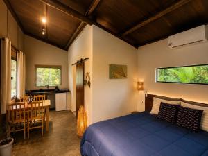 a bedroom with a blue bed and a table and chairs at Jardim Mirim in Cananéia