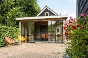 a house with glass doors and chairs on a patio at B&B by lin in Dodewaard