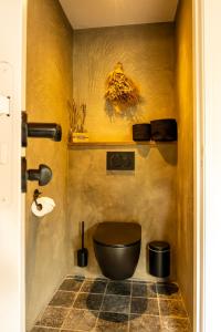 a bathroom with a black toilet in a yellow wall at B&B by lin in Dodewaard +8 photos