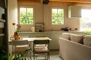 a kitchen with a table and chairs and two windows at B&B by lin in Dodewaard