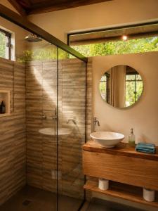 a bathroom with a shower with a sink and a mirror at Jardim Mirim in Cananéia +59 photos