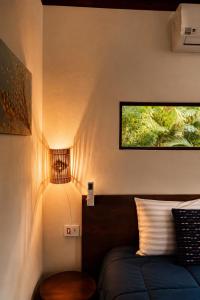 a bedroom with a bed and a lamp on the wall at Jardim Mirim in Cananéia