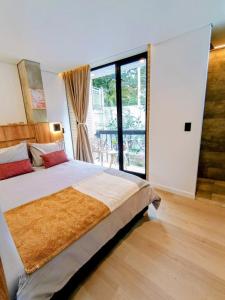 a bedroom with a large bed and a large window at Iwana stay in Bogotá