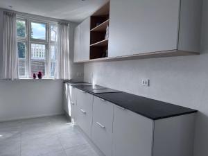 a kitchen with white cabinets and a black counter top at Tønder Byhus in Tønder +16 photos