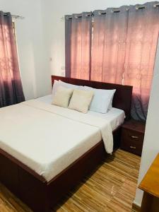 a bed with white sheets and pillows in a room at Joyet Guest House in Amasaman