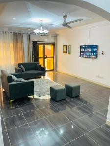 a living room with two couches and a tv at Joyet Guest House in Amasaman