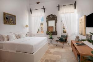 a white bedroom with a bed and a mirror at Allium Art House Symi in Symi