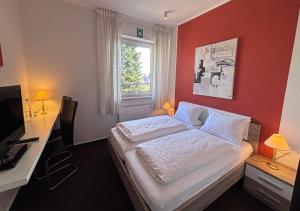a bedroom with a bed and a desk and a window at Hotel van Lendt garni in Dülmen