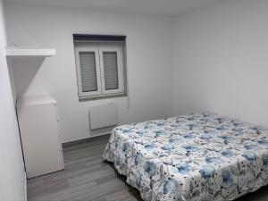 a bedroom with a bed in a white room with a window at Casa Costa in Esmoriz
