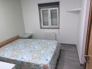 a bedroom with a bed with a floral comforter and a window at Casa Costa in Esmoriz +5 photos