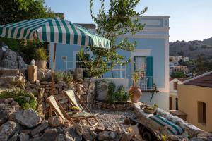 a patio with chairs and an umbrella in front of a building at Allium Art House Symi in Symi
