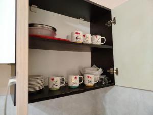 a cupboard with plates and mugs in a kitchen at Tamari in Ureki