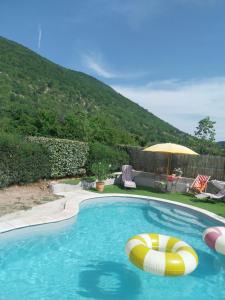 a swimming pool with a beach ball and an umbrella at L'olivier sur la place in La Rochegiron