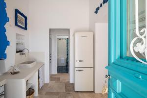 a white refrigerator in a bathroom with a blue door at Allium Art House Symi in Symi +34 photos
