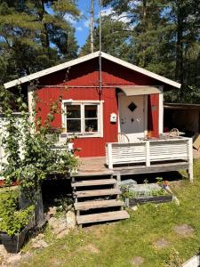 a red barn with a porch and stairs to it at Tiny house at Enhrna in Enhörna