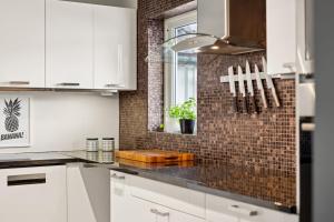 a kitchen with white cabinets and a brick wall at Vinkelgata 20 Guesthouse in Stavanger +21 photos