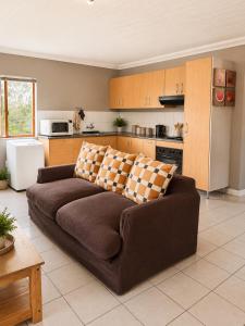 a living room with a brown couch in a kitchen at The Upper Deck Apartment in Swellendam
