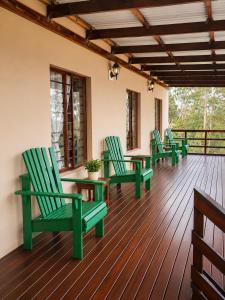 a deck with green chairs and tables on a porch at The Upper Deck Apartment in Swellendam