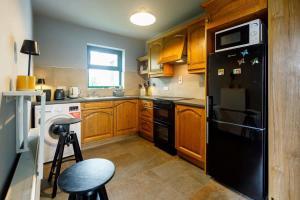 a kitchen with wooden cabinets and a black refrigerator at The Tailor's Cottage in Lahinch