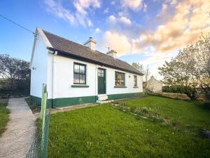 a white house with a green door in a yard at The Tailor's Cottage in Lahinch