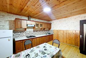 a kitchen with wooden cabinets and a table and a refrigerator at Gabala Grean Villa in Gabala