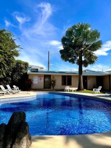 a swimming pool with a palm tree and a building at Hotel La Punta in Puntarenas +10 photos