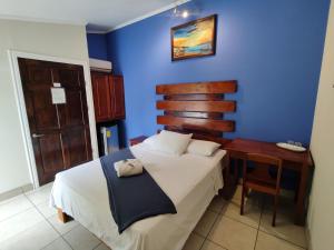a blue bedroom with a bed and a desk at Hotel La Punta in Puntarenas
