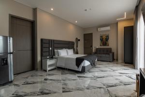 a hotel room with a bed and a refrigerator at Hotel Colores Estadio in Medellín
