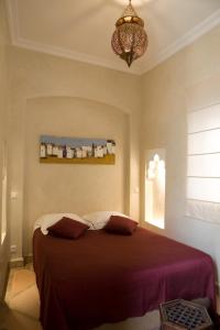 a bedroom with a bed with a purple blanket at Riad Les Hibiscus in Marrakech